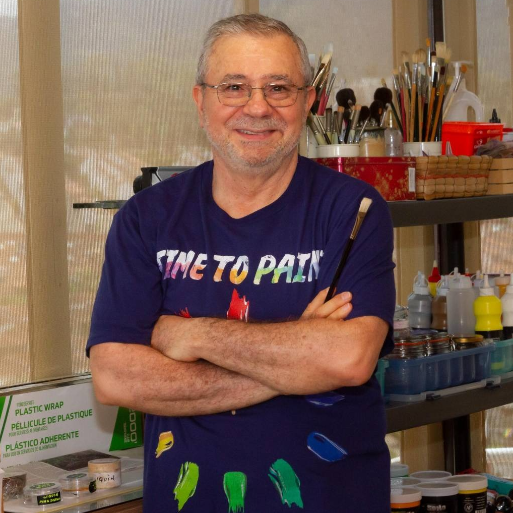julio vargas the artist, holding a brush, while posing in his home studio